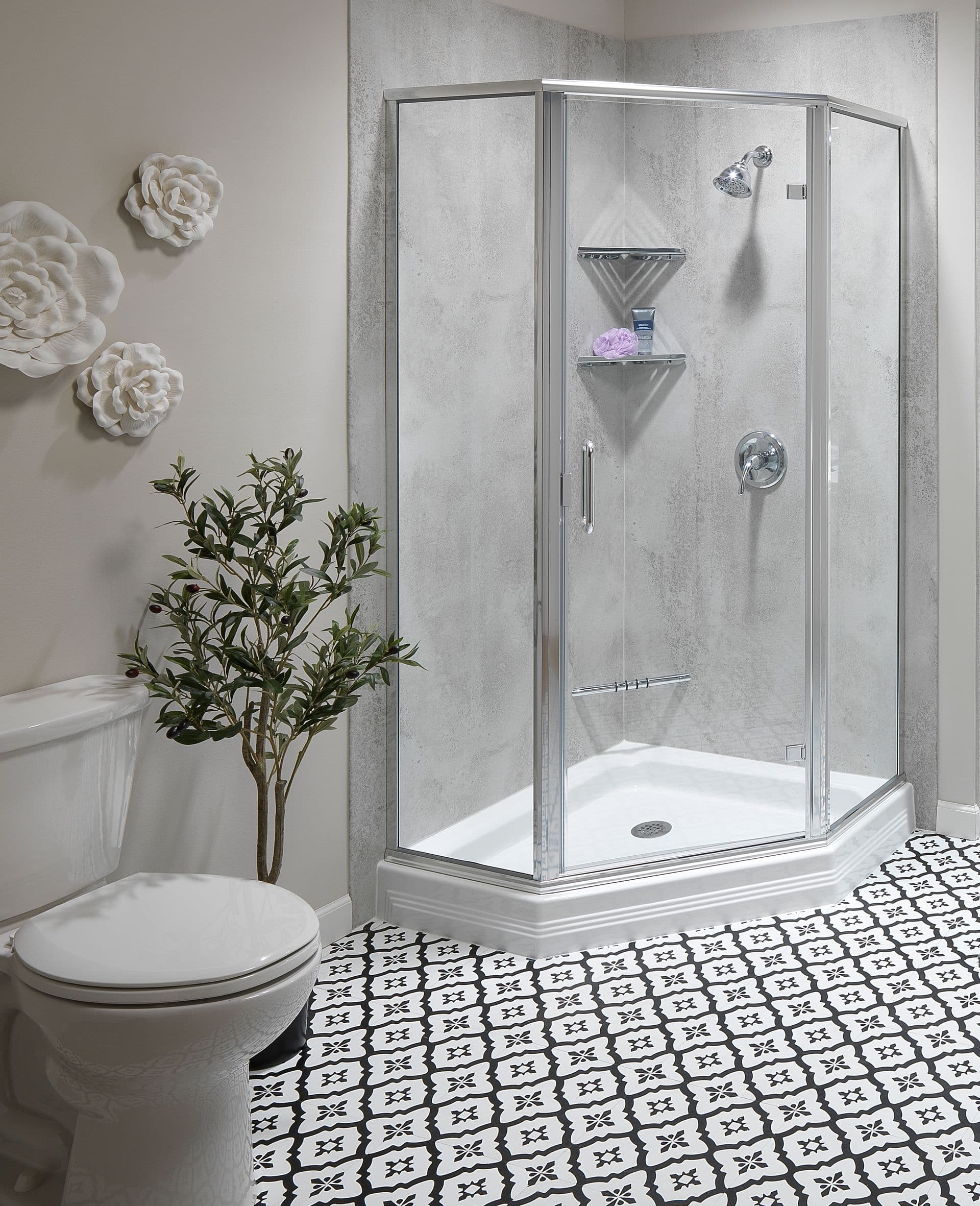 A contemporary bathroom featuring a corner glass shower, patterned black and white floor tiles, and decorative wall flowers.