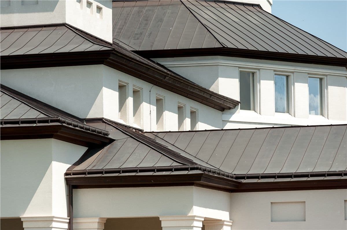 A close-up of a contemporary building's white walls and dark metal roofing with geometric windows.